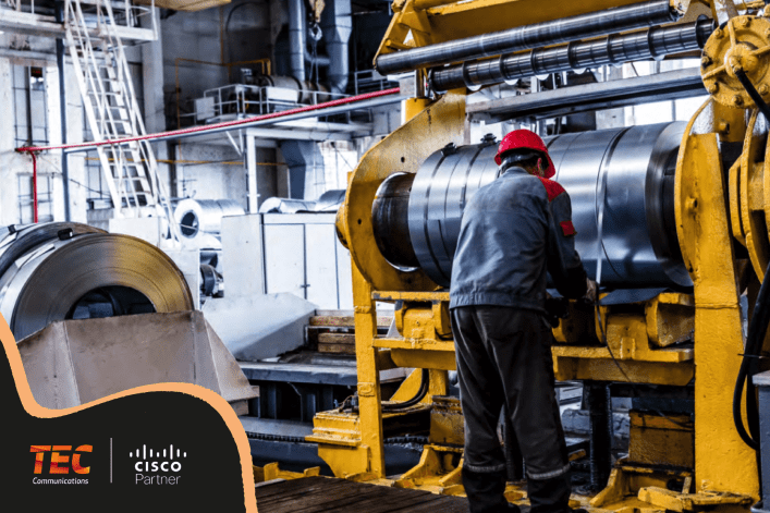 A worker in a red helmet operates machinery in an industrial setting