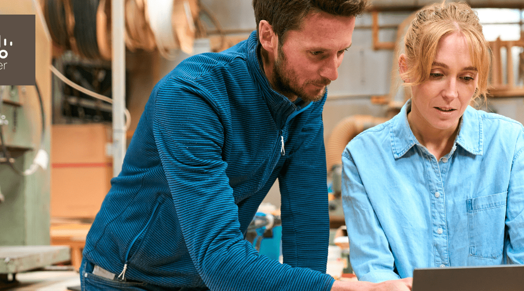 Male And Female Carpenters Working In Woodwork Workshop Using Laptop Together