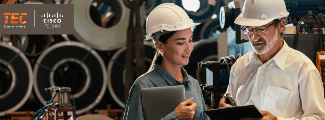 Two professionals in safety gear having a discussion on a production floor of a manufacturing facility